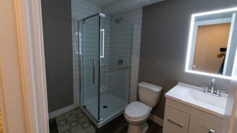 LED mirror in basement bathroom with tiled shower