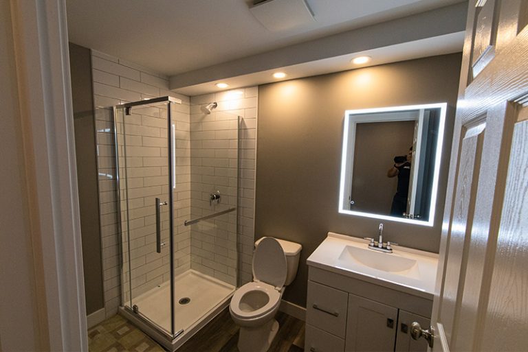 basement full bathroom with tiled shower and vinyl flooring