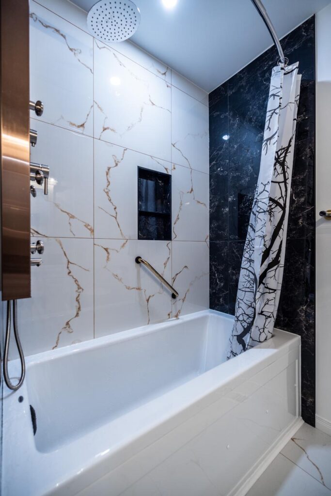 Bathroom renovation in Ottawa tub and large tile walls black and white tiles copper mixing valve