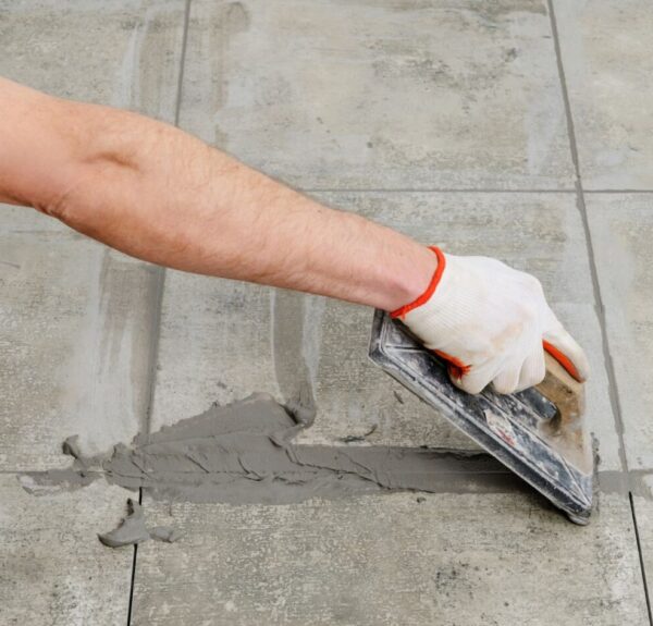 I hand putting grout on a tile during bathroom renovation