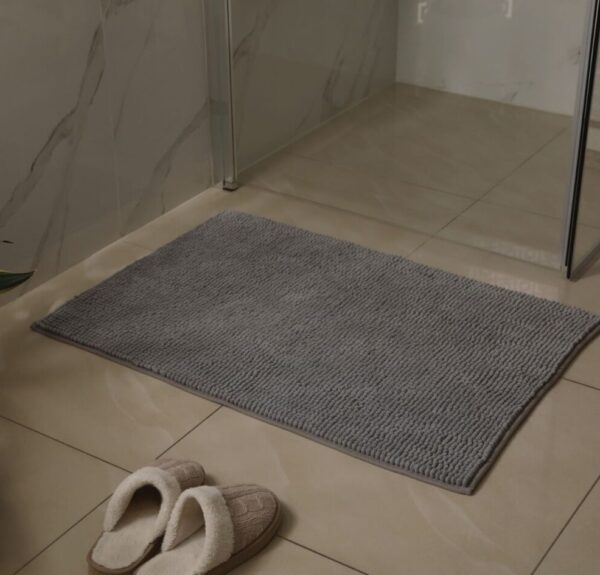 A modern bathroom featuring a shower and a soft gray rug on the floor, creating a serene and stylish atmosphere.