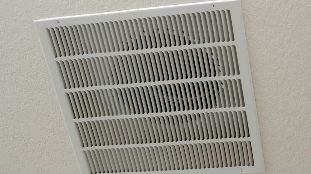 A white air vent installed on a ceiling, providing ventilation and air circulation in the bathroom.