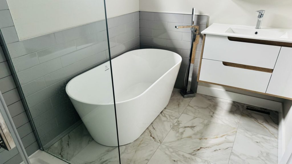 A sleek modern bathroom featuring a stylish bathtub and a contemporary sink against a minimalist backdrop after bathroom renovation in Ottawa